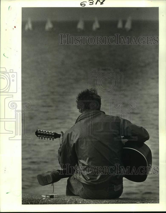 1988 Press Photo Pierre Legrand plays his guitar on the breakwater of Lakefront - Historic Images