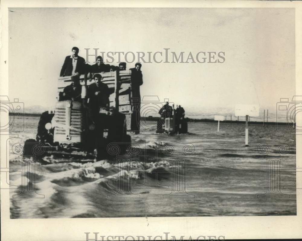 1969 Iranian farm workers use tractors to travel flood-covered road - Historic Images