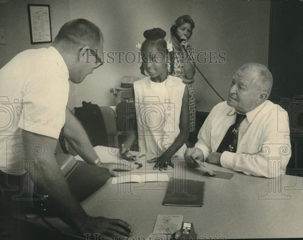 Press Photo Group sits together and talks while women in background on phone - Historic Images