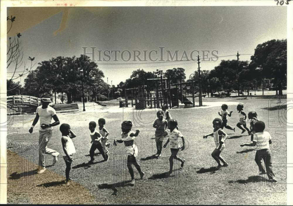 1979 Roussell Johnson playing with children at the playground - Historic Images