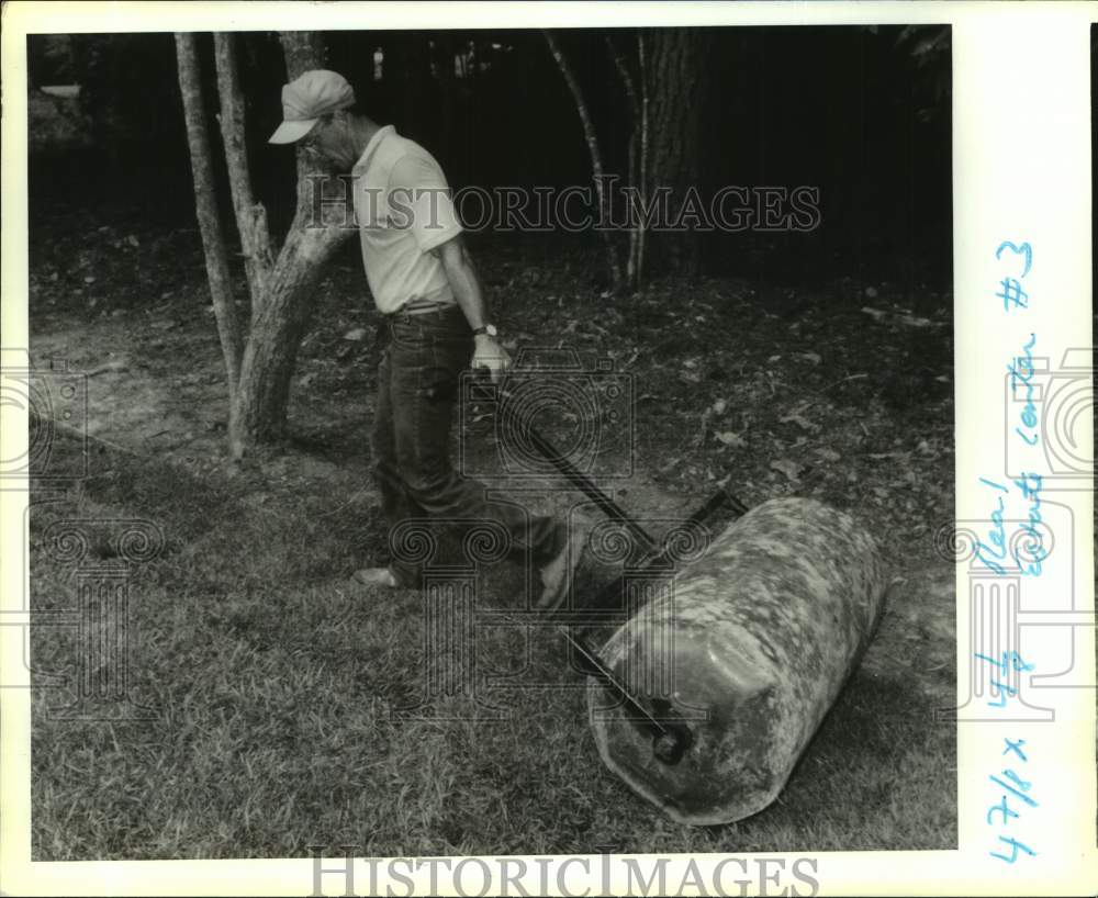 1990 Press Photo Charlie Jones, landscape contractor rolls out sod - Historic Images