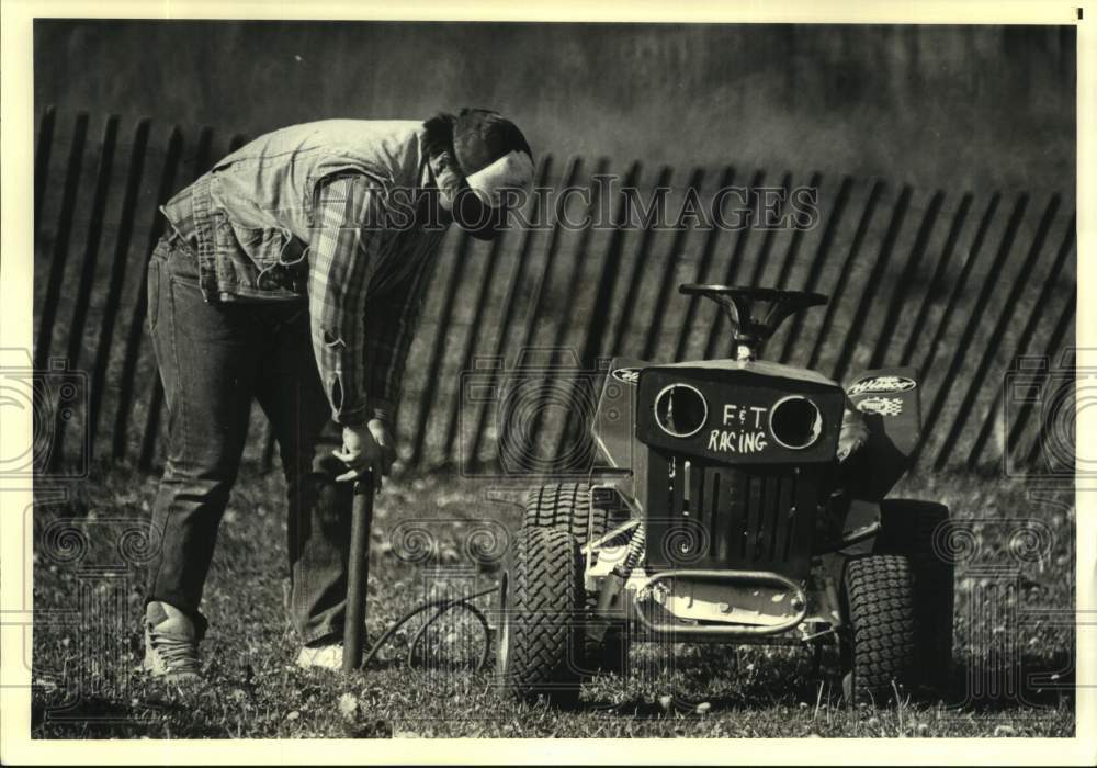 1986 Press Photo Lawn mower racer pumps up his mower tires before race - Historic Images