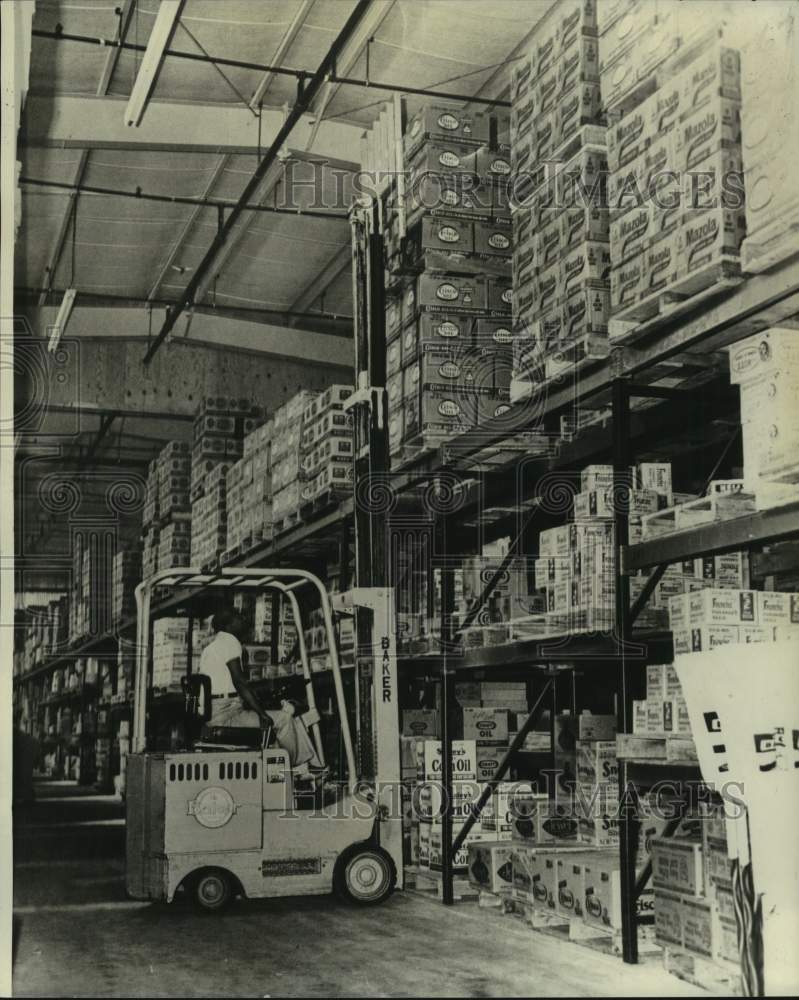 1978 Warehouseman operating a forklift to stack goods for storage. - Historic Images