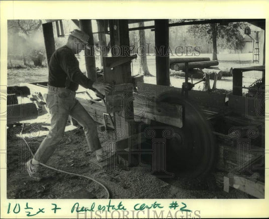 1990 Press Photo John LeMeur uses his outdoor sawmill to cut cypress board - Historic Images