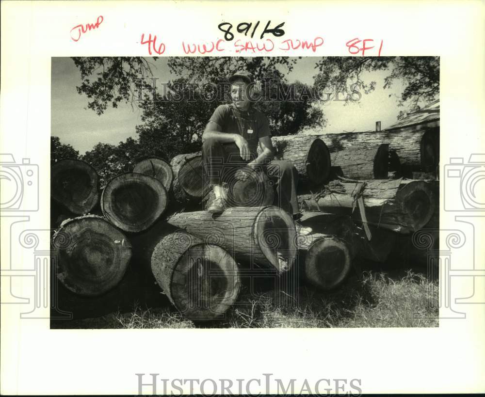 1986 Press Photo John LeMeur sits atop a stack of cypress logs in Algiers - Historic Images