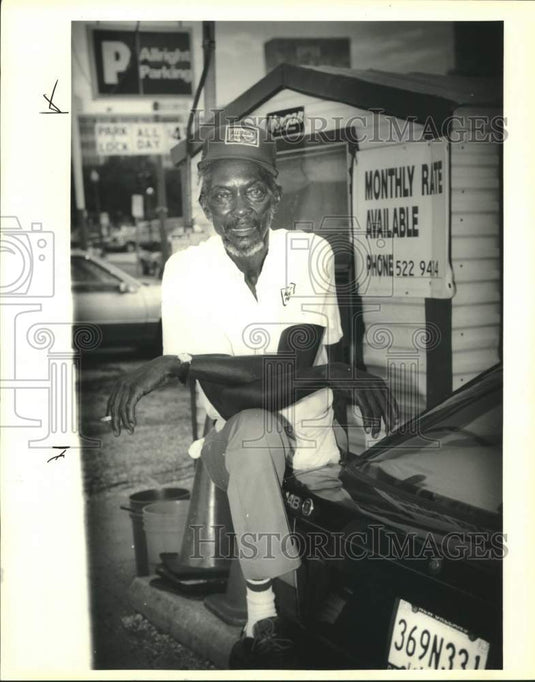 1991 Press Photo Elie Lewis sitting in front of the Allright Lot where he works. - Historic Images