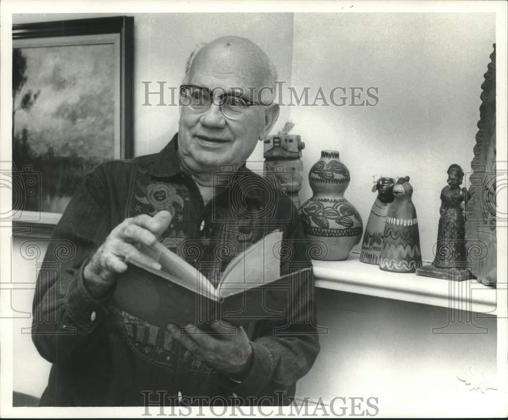 1972 Harold Lovy in front of his mantel with native art works. - Historic Images