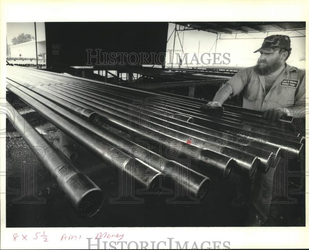 1989 Press Photo Tommy Landry rolls coated pipes at Land and Marine Rental Co. - Historic Images