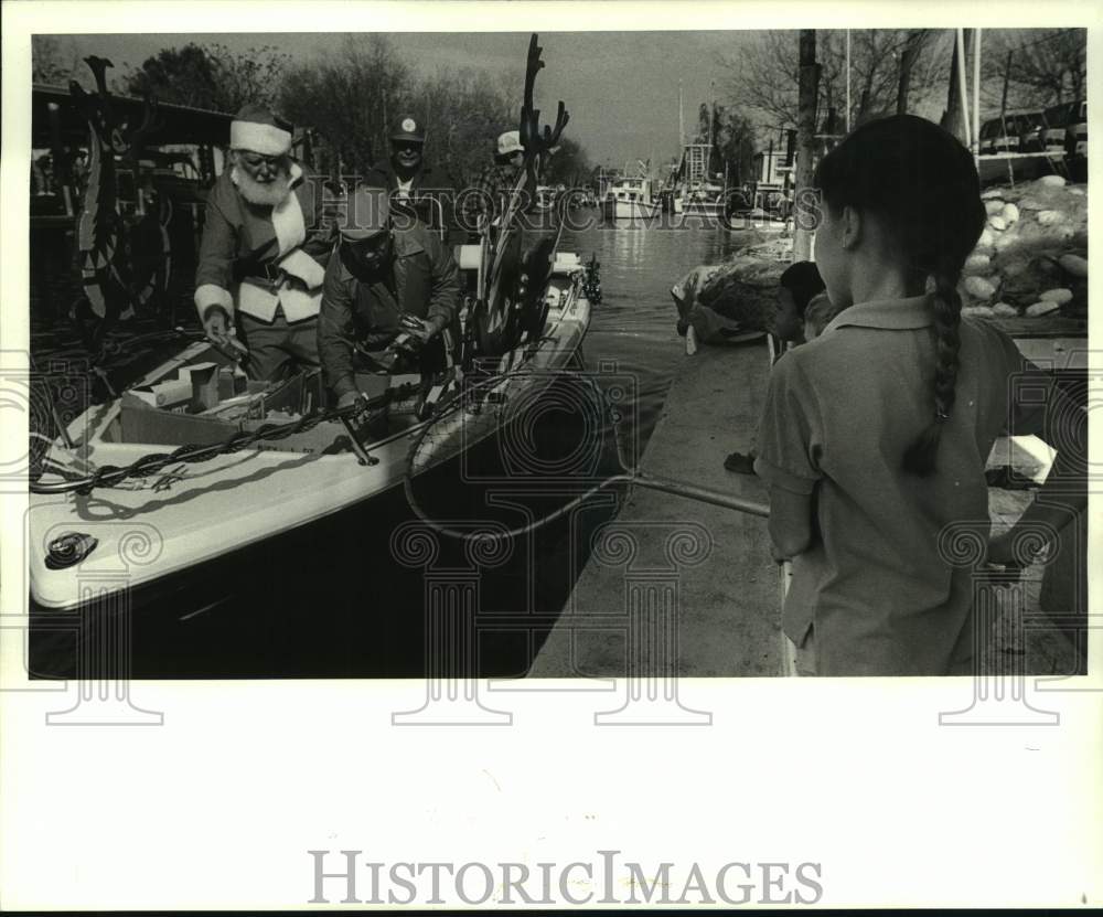 1987 Press Photo Lisa Martinez receives a gift given by the Santa boat - Historic Images