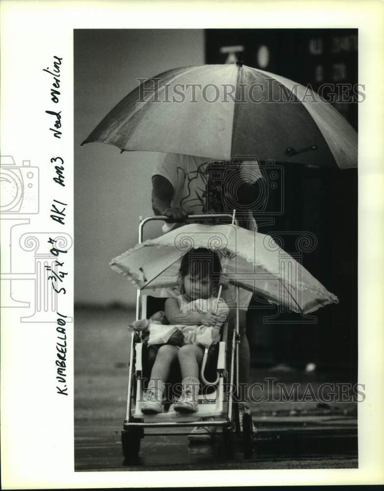 1992 Press Photo Christine using two umbrellas to stay dry in Metairie. - Historic Images