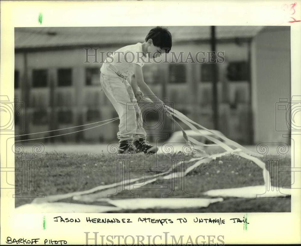 1989 Press Photo Jason Hernandez attempts to untangle kite tail - Historic Images