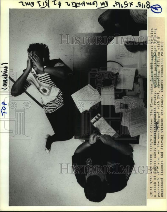 1991 Press Photo Officer Tim Flynn waits for a DWI suspect to sign papers. - Historic Images