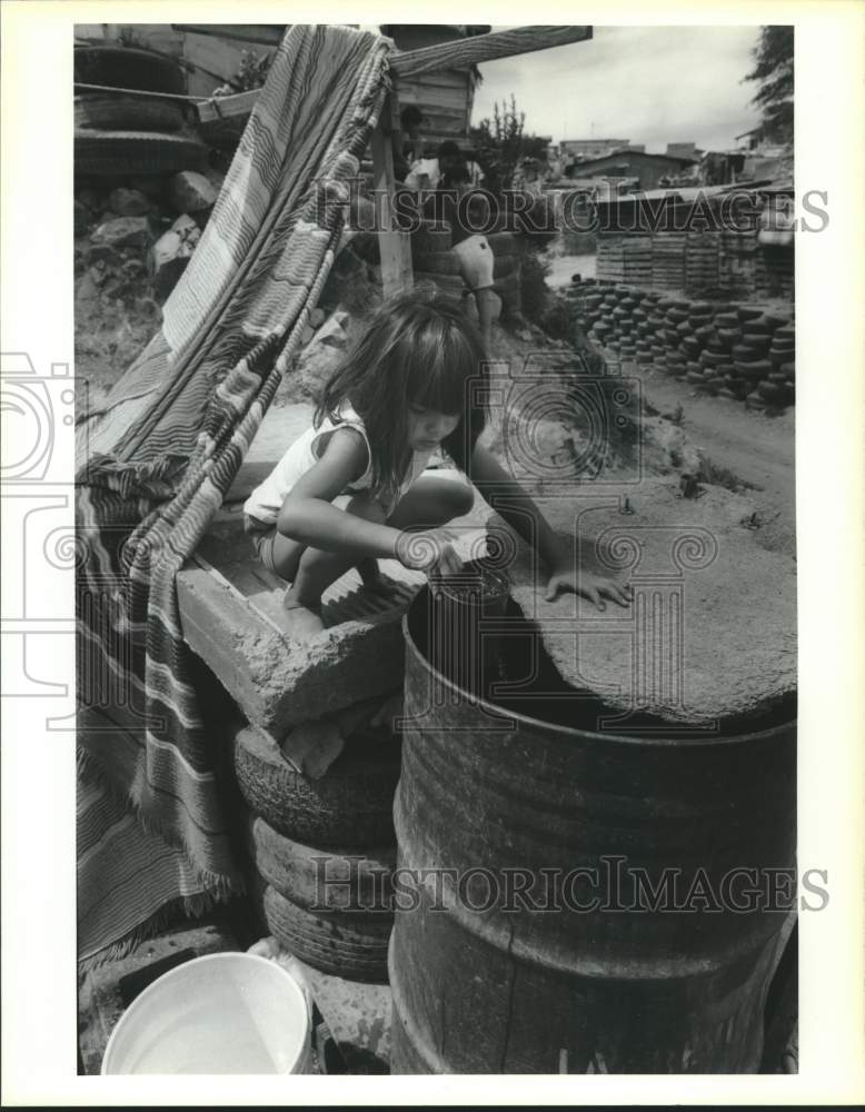 1991 Press Photo Rachelle Guadalupe, playing in water barrel at Los Tapiros - Historic Images