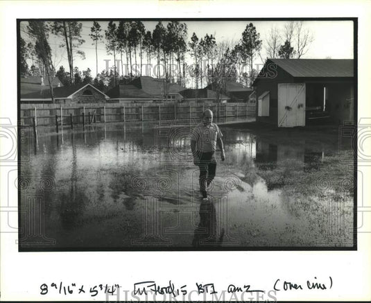1992 Press Photo Charles T. Martin walking through the water standing in yard. - Historic Images