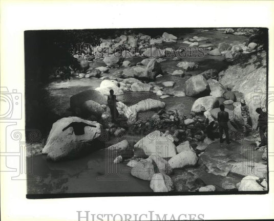 1991 Press Photo Men working in rocks in river slowing flow to aid chlorination - Historic Images