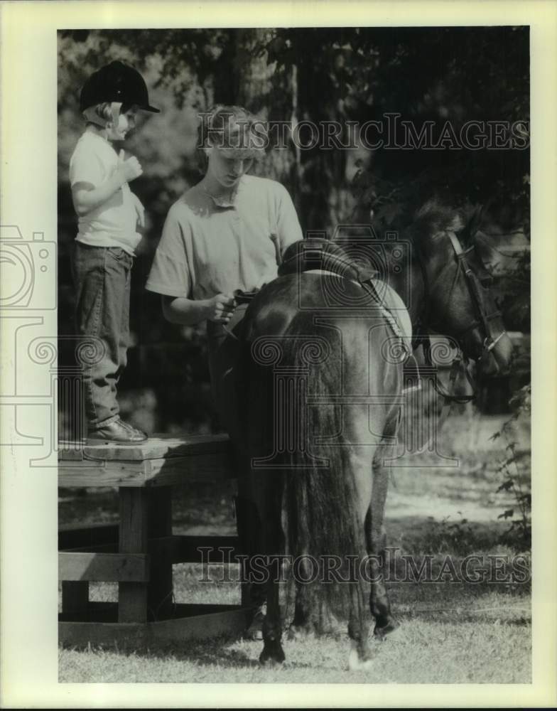 1989 Press Photo Marti Laramee checks saddle while Molly Evers get ready - Historic Images