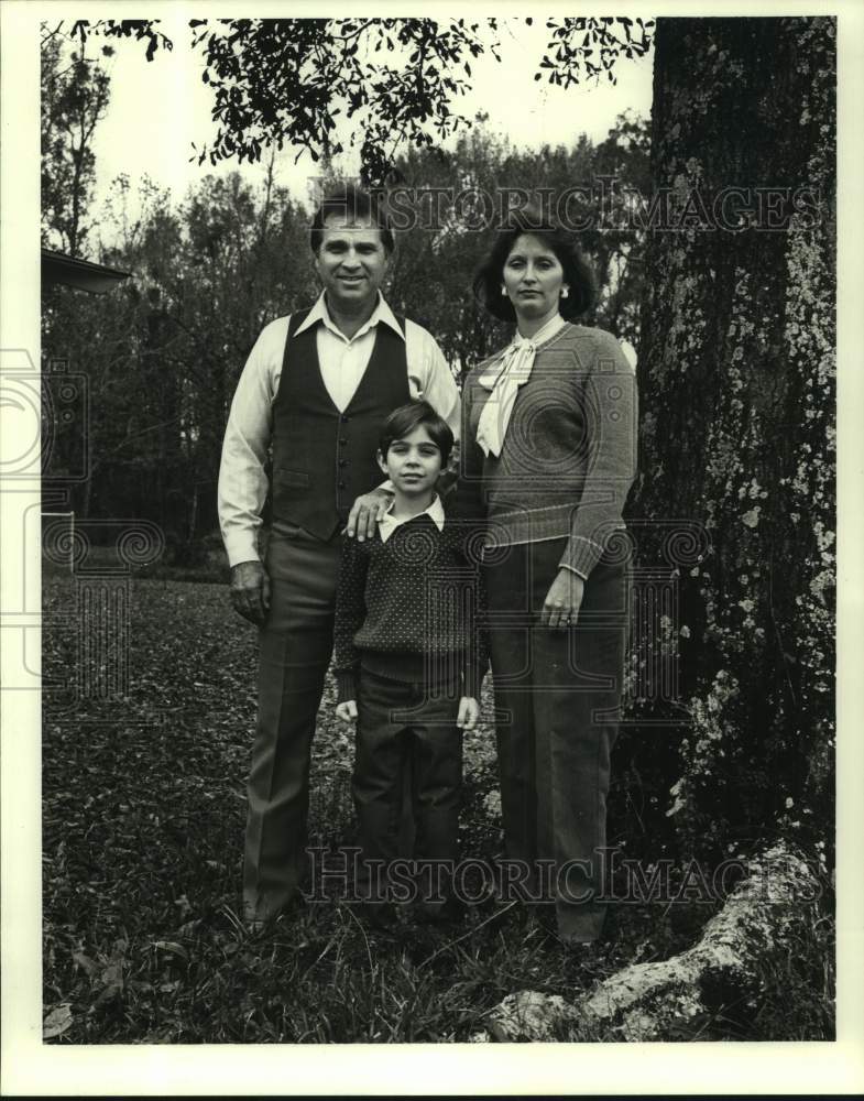 1987 Press Photo Ross Maggio, Jr. with his wife and son posing under a tree - Historic Images