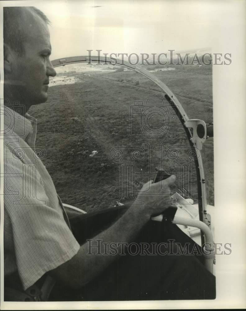 1968 Helicopter pilot Chuck Bramlett above a marshy area of the city - Historic Images