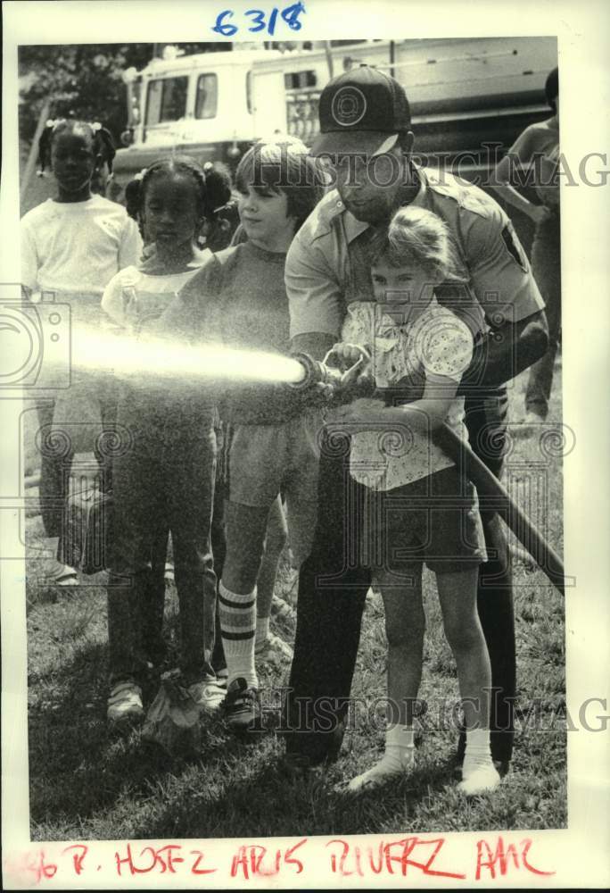 1984 Fireman Ellis Richard shows Brandy Gaubert how to hold a hose - Historic Images