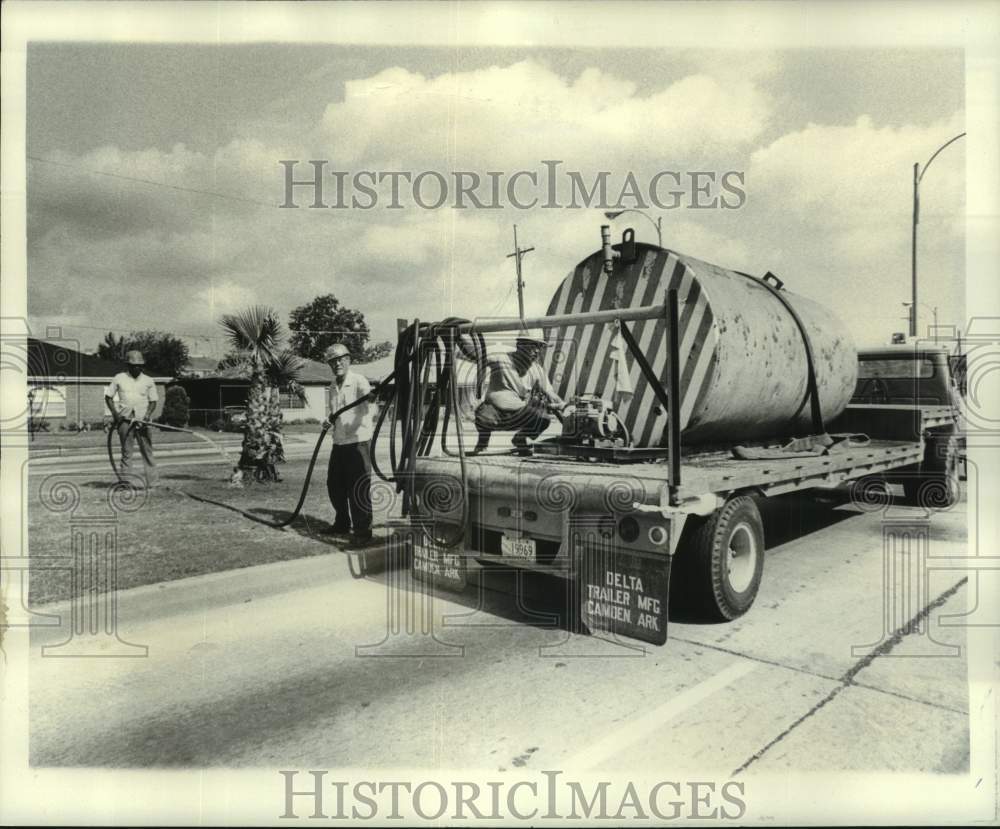 1977 Superintendent Jim Finnan handles hose to water parkways - Historic Images