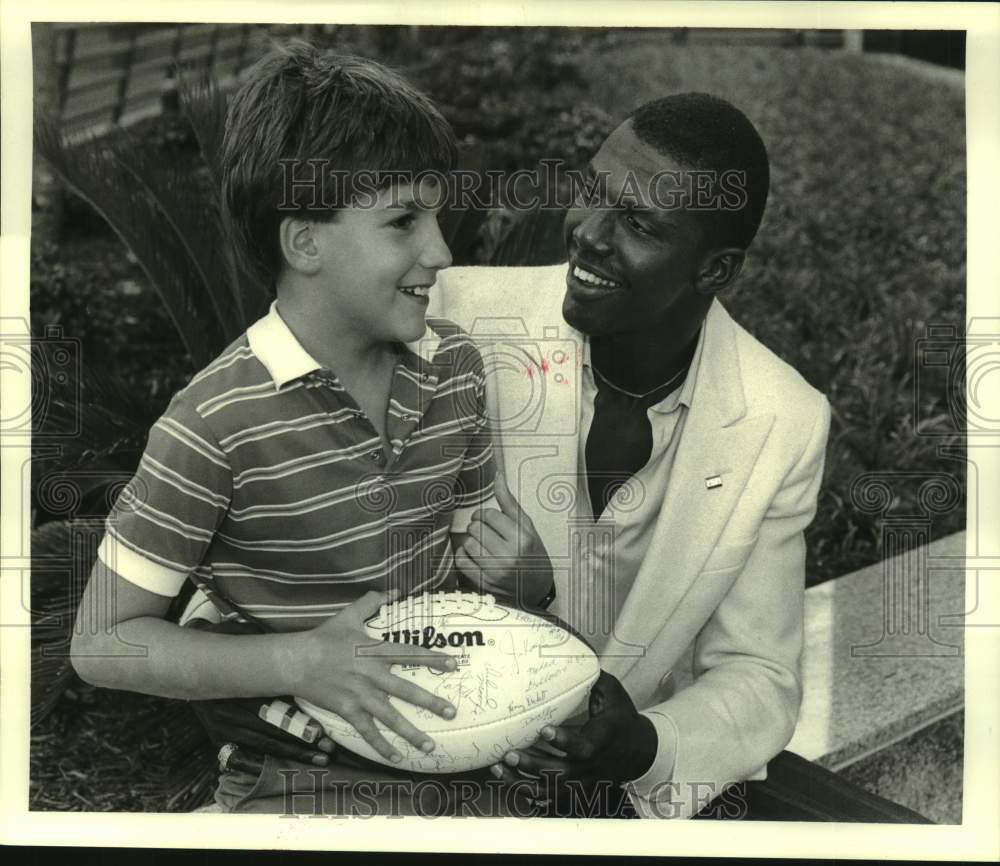 1984 Press Photo Saints player Tyrone Young gives Kevin Barrios football - Historic Images