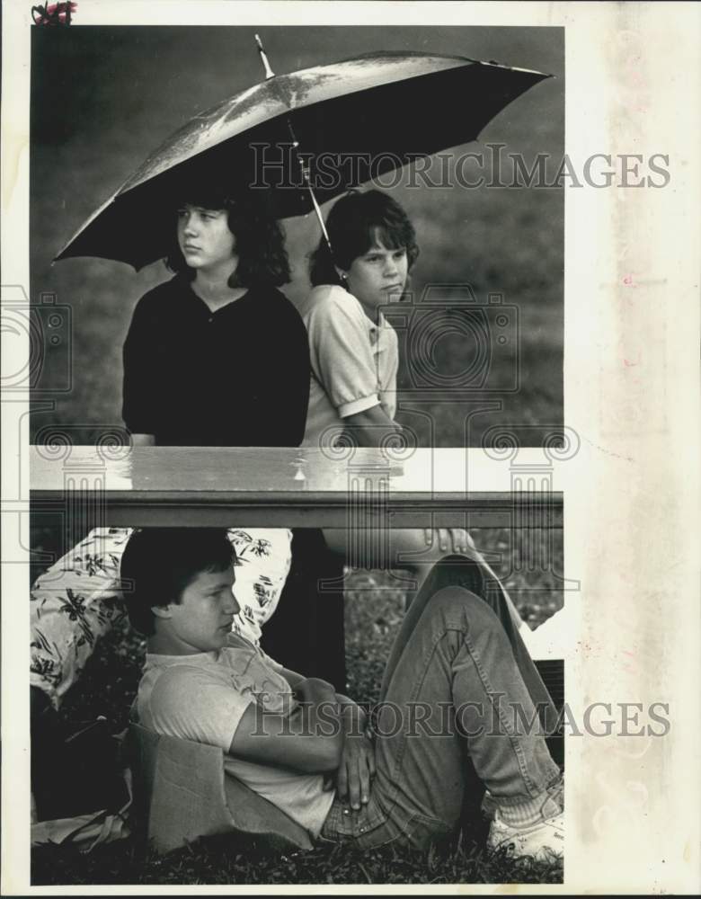 1987 Press Photo Teenagers watch football practice in the rain at East John High - Historic Images