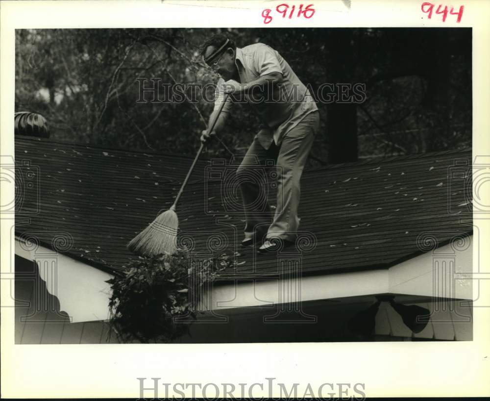 1989 Howard Stanga sweeps leaves off the roof of his mother-in-law. - Historic Images