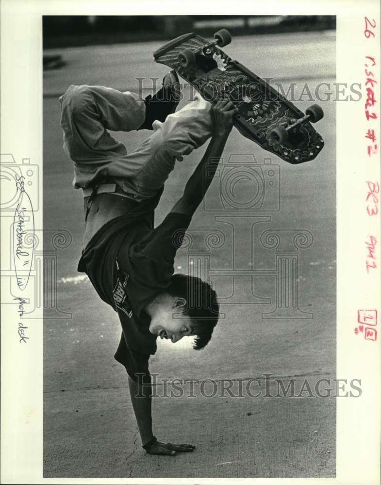 1987 Press Photo Youngster does handstand while holding on skateboard - Historic Images