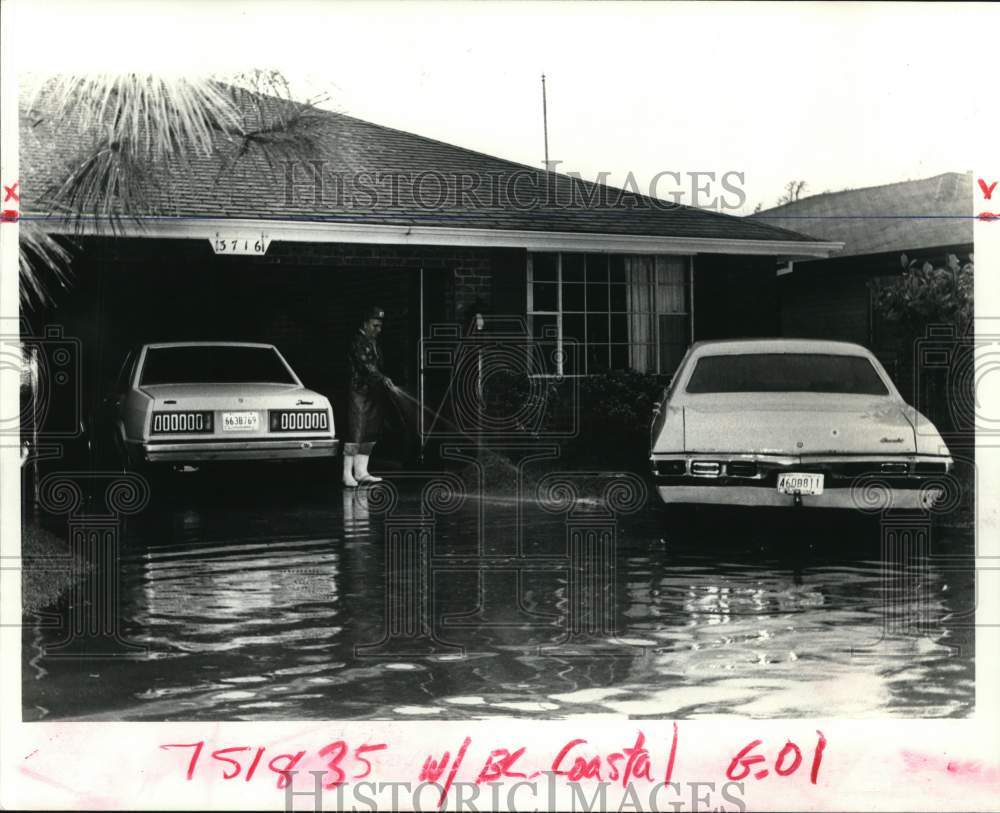 1983 Press Photo Leon Pecoraro hoses debris from rising water in Chalmette - Historic Images