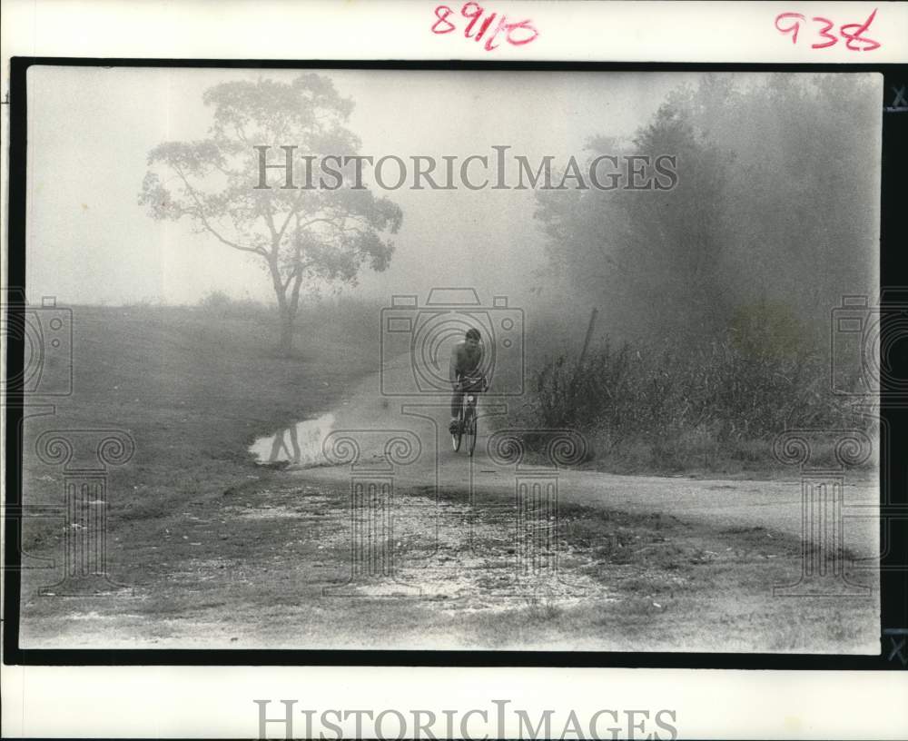 1988 Louis Bienvenue rides his bike out of the fog to Kenner-Historic Images