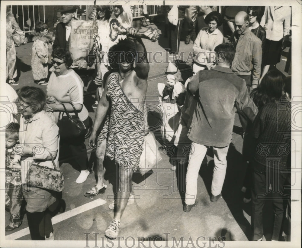 1968 man dressed as a caveman enjoying the carnival  - Historic Images