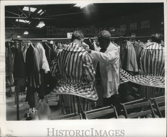 1963 Rex Krewe member dons clown costume with help of attendant. - Historic Images