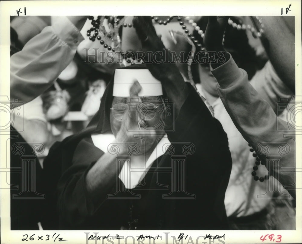 1989 Nun reaches for beads with the Mardi Gras crowds in New Orleans - Historic Images