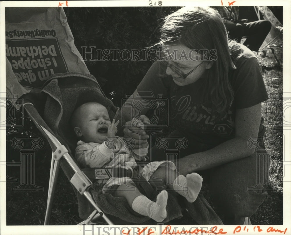 1982 Laura Herbert comforts baby at Mardi Gras Krewe du Monde parade - Historic Images