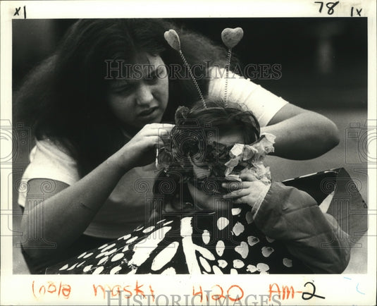 1983 Adult Helps Young Girl with Mask, Mardi Gras, New Orleans - Historic Images