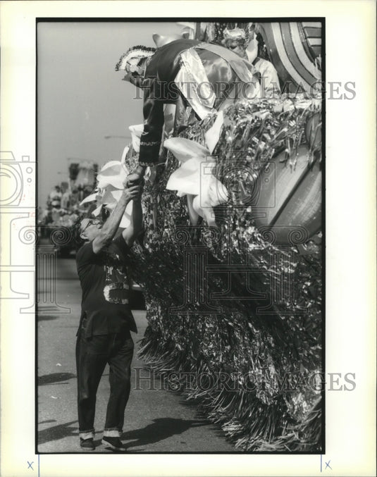 1990 Carnival Parade goer gets cup full of beads from a rider. - Historic Images