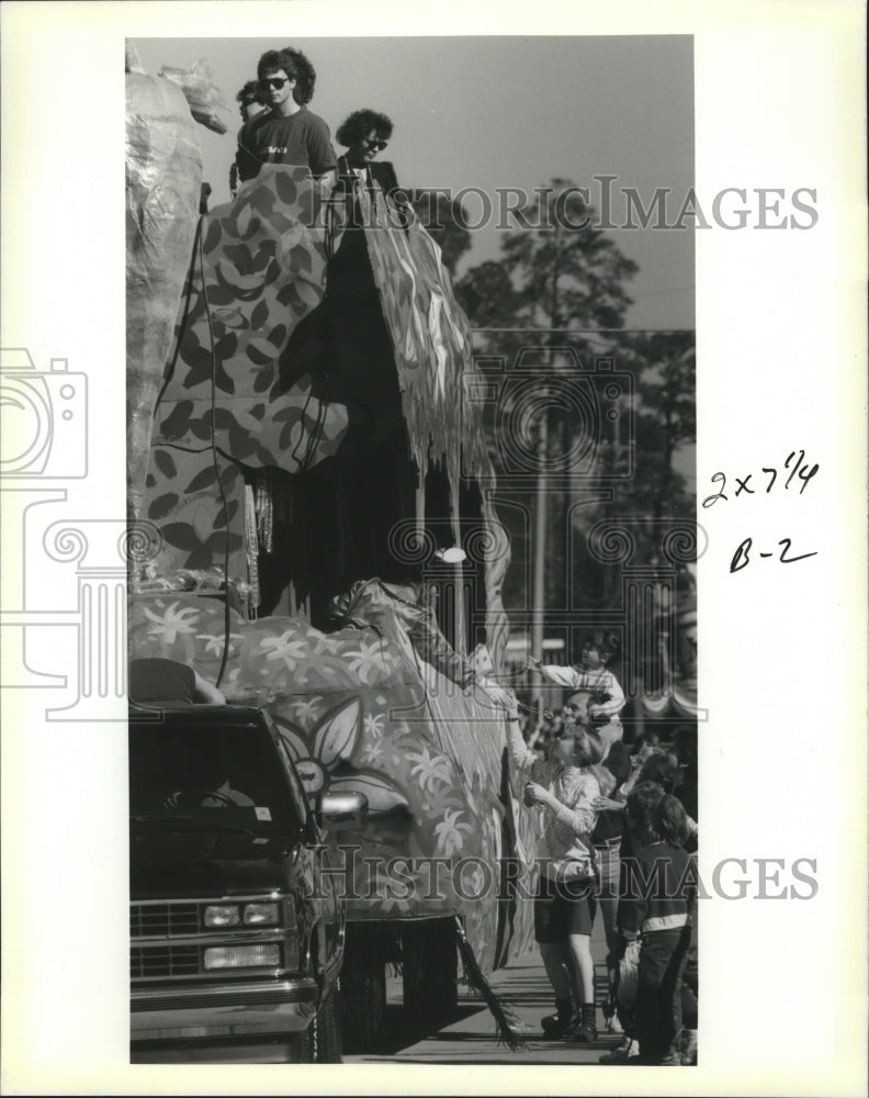 1990 Carnival spectators reach for beads as a float rolls by. - Historic Images