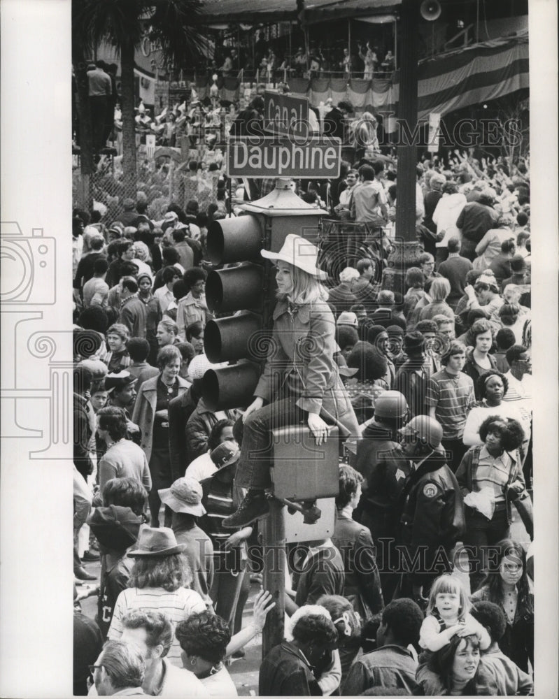1973 Carnival spectator perched high on Canal and Dauphine light. - Historic Images