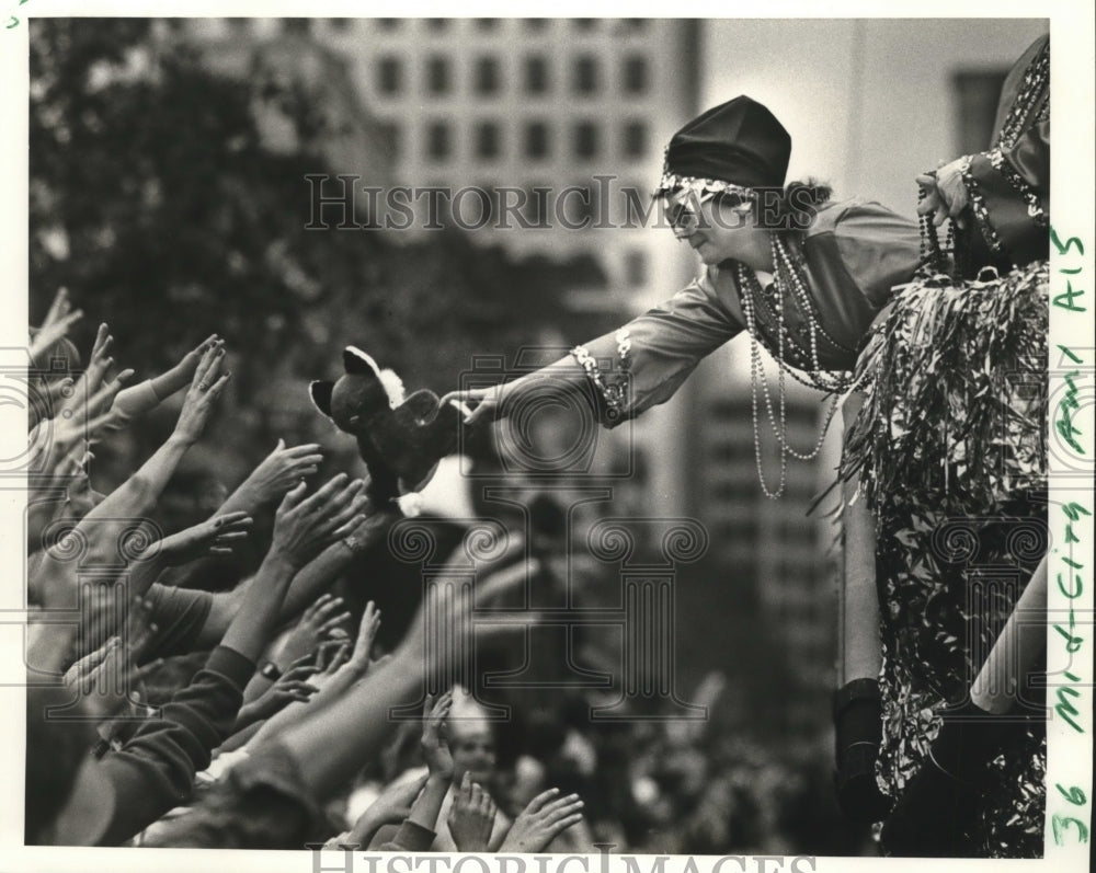 1986 Masker Hands out Stuffed Animal at Mid - Historic Images