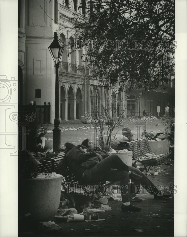 1982 People Sleeping on Benches Surrounded by Trash from Carnival - Historic Images