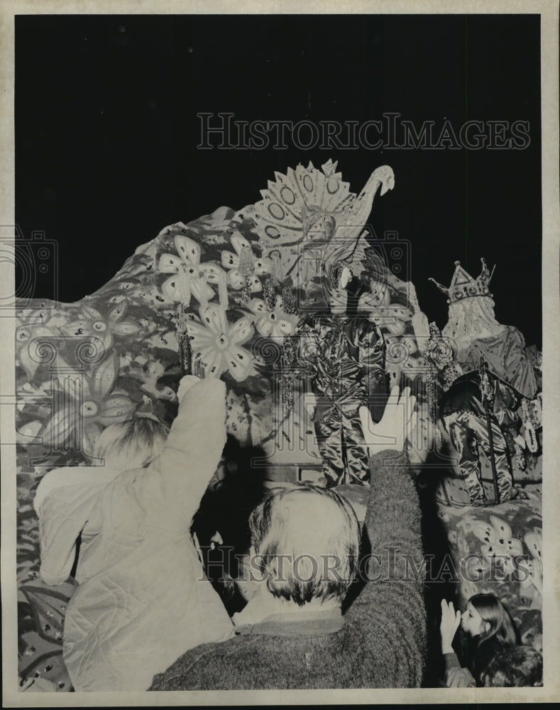 1974 Carnival Parade Hands reach out to float with giant peacock. - Historic Images