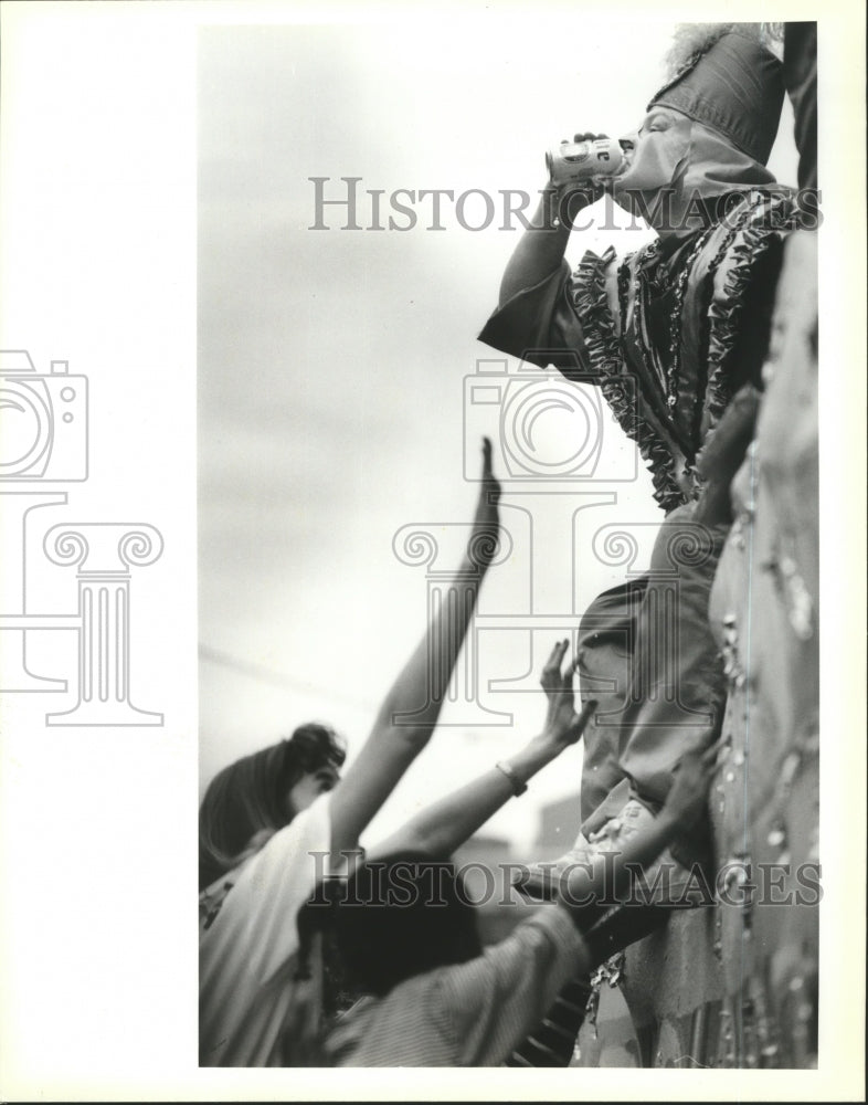 1991 Rex krewe member drinks a beer at the Rex Mardi Gras parade - Historic Images