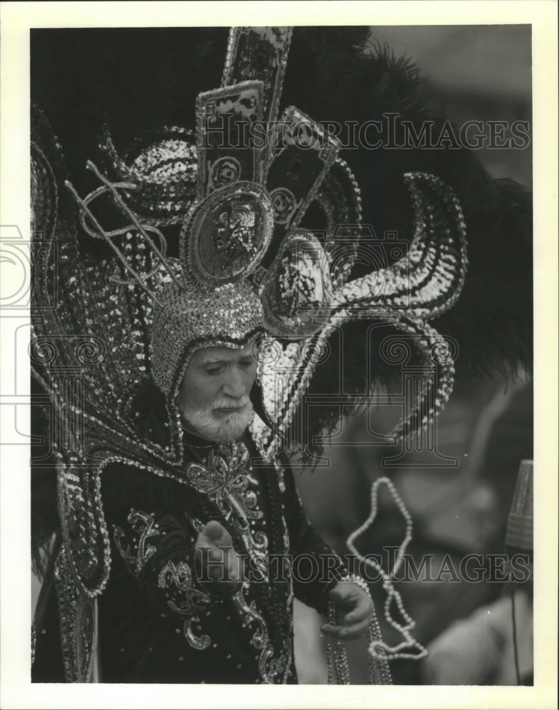 1990 Krewe of Troy member tosses beads during the Mardi Gras parade - Historic Images