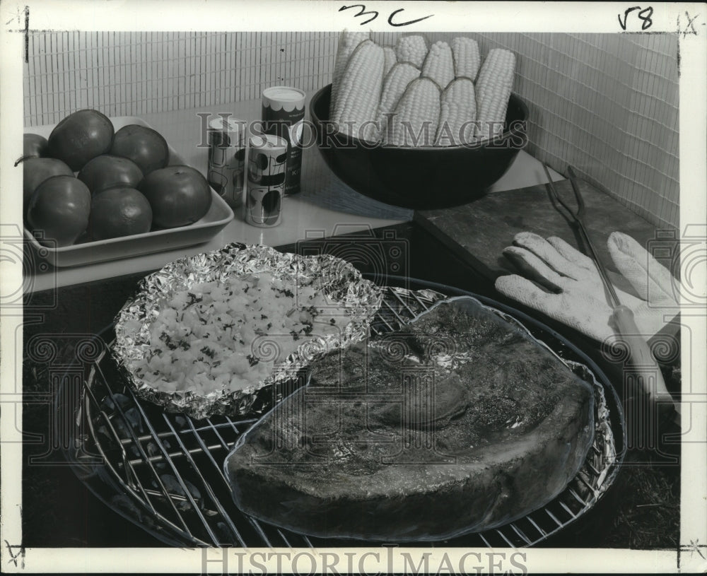 Press Photo Grilled Steak and foil pack of onions to be served with fresh corn - Historic Images