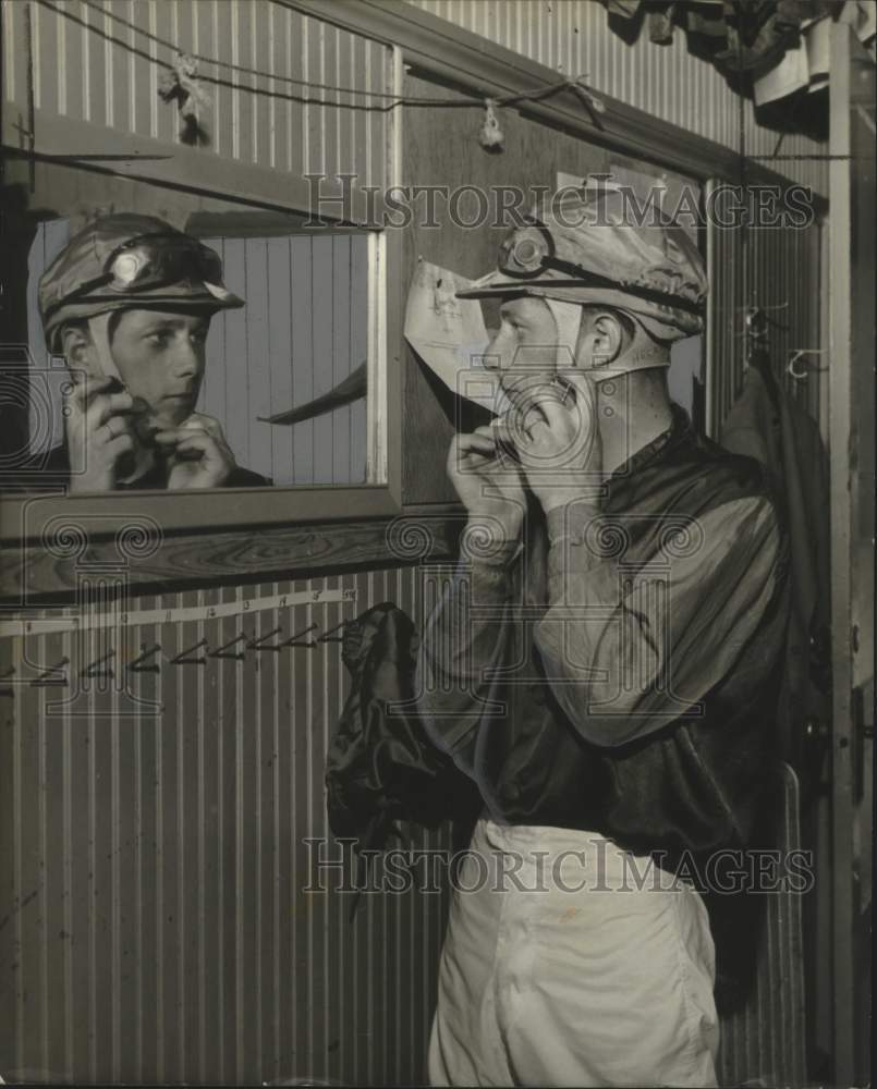 Press Photo John Heckman, horse racing jockey, puts on his helmet - Historic Images