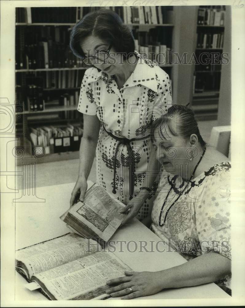 1976 Assistants hold ancient dictionary at Tulane University library - Historic Images