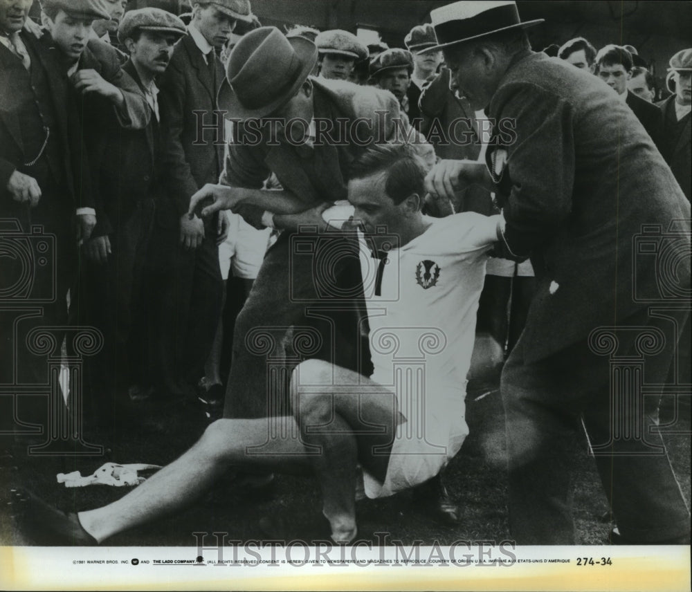 1981 Two men helping a fallen runner in a crowd, &quot;Chariots of Fire&quot; - Historic Images