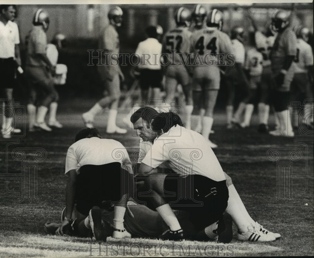 1976 New Orleans Saints- Stram bends over Terry Schmidt on field. - Historic Images