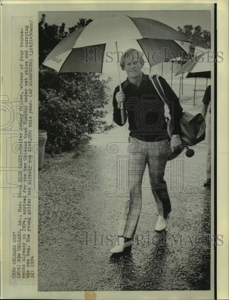 1974 Press Photo Golfer Johnny Miller holds umbrella and carries his clubs in NO - Historic Images