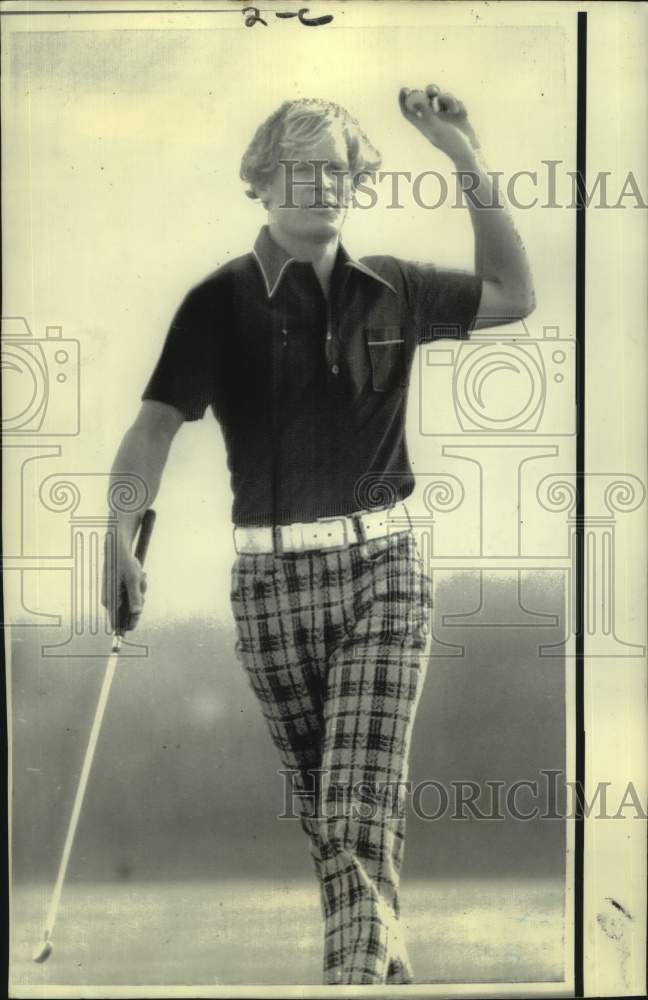 1974 Press Photo Golfer Johnny Miller raises his fist with ball, putter in hand - Historic Images